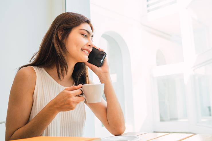 donna al telefono con tazzina caffè