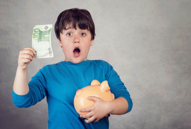 bambino sbalordito con salvadanaio e 100 euro in mano