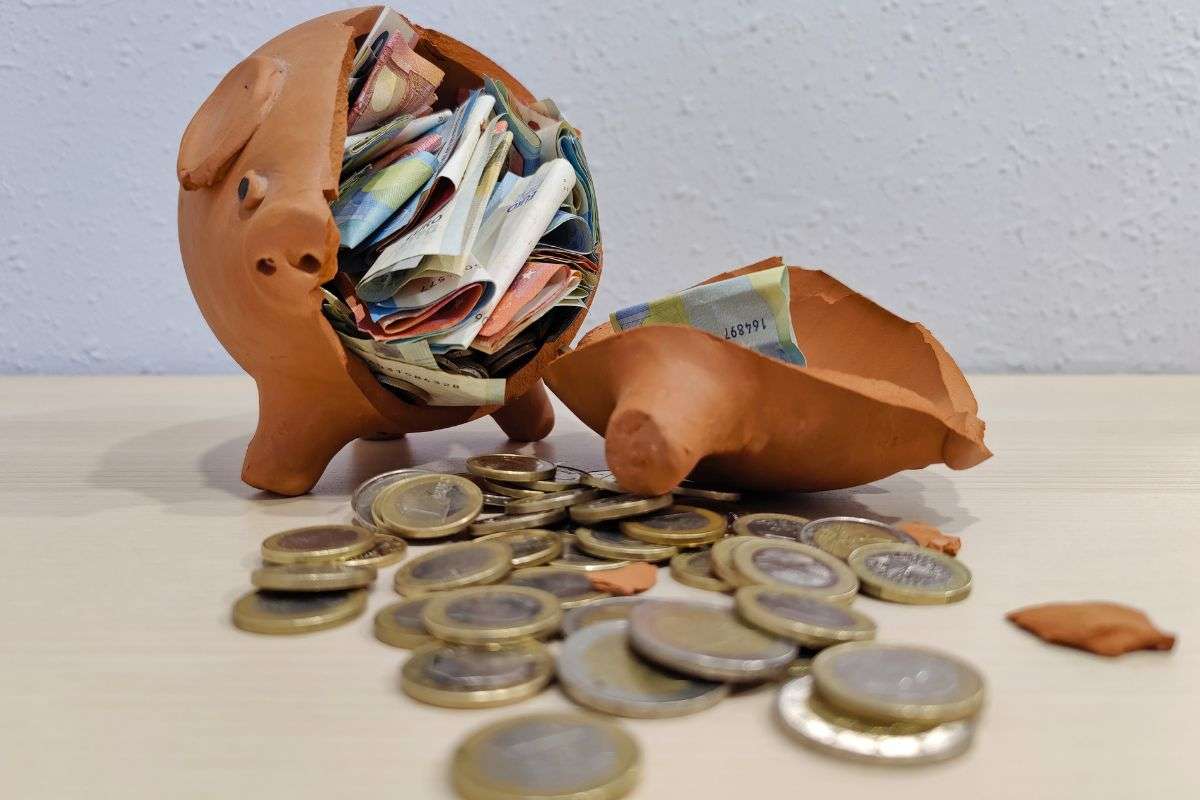 salvadanaio rotto con banconote e monete