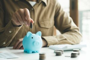 persona che fa calcoli e mette moneta nela salvadanaio